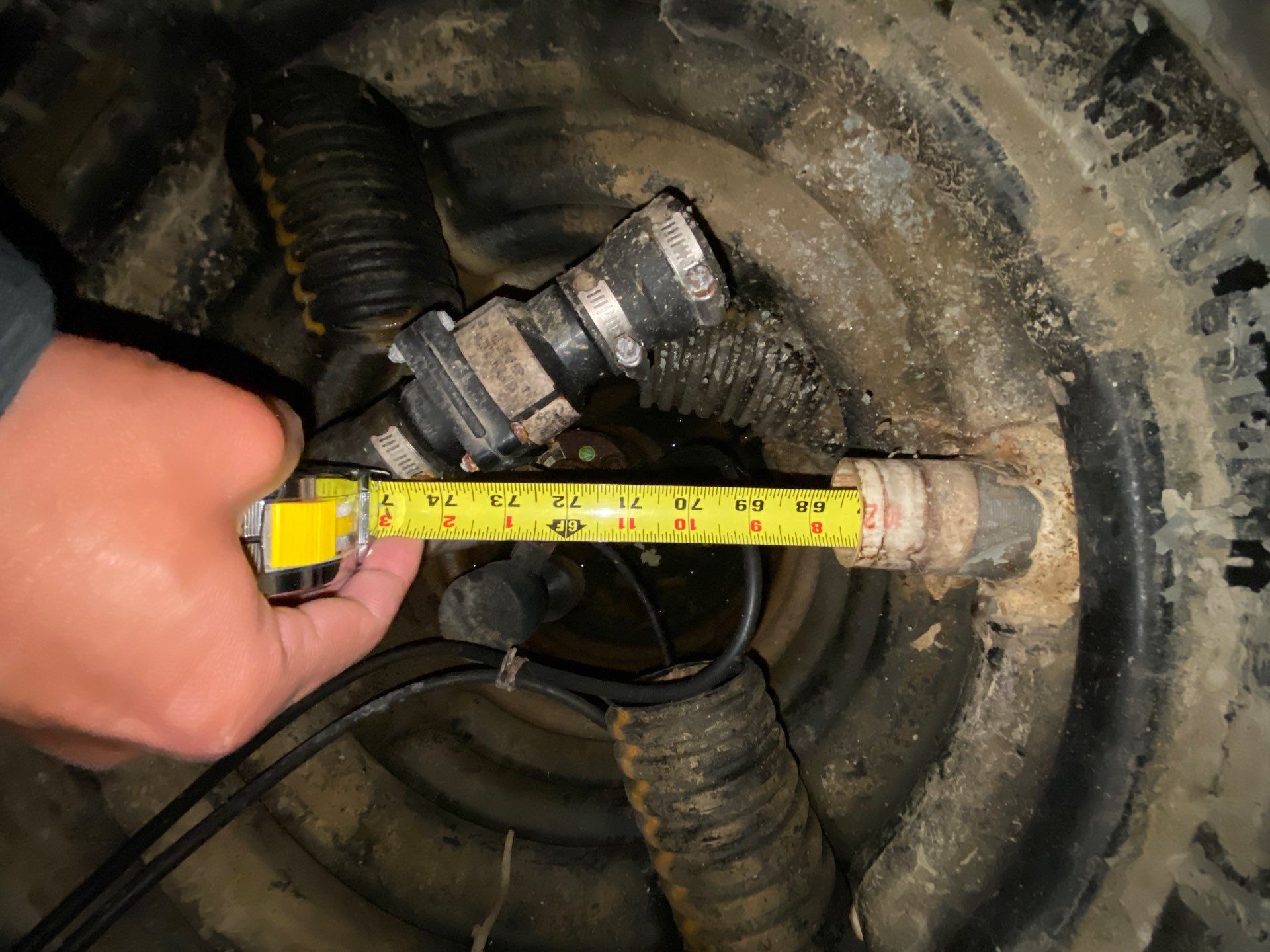 Epp Foundation Repair technician inspecting and measuring a sump pump drainage system in a crawl space in Omaha, NE.