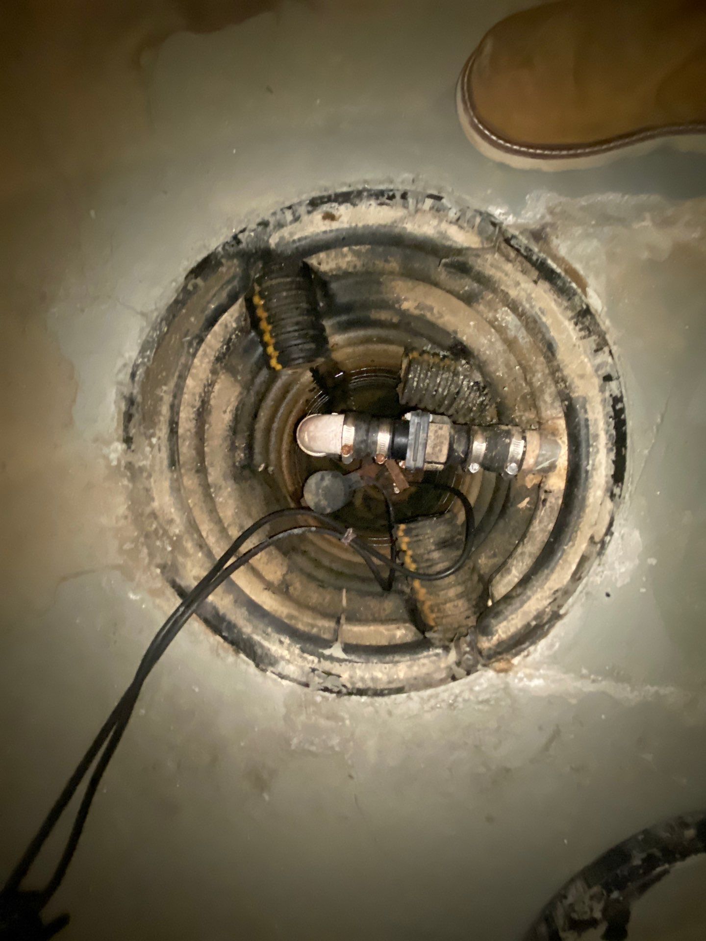 Epp Foundation Repair inspecting a sump pump in a flooded basement pit, addressing basement flooding and water damage in Omah