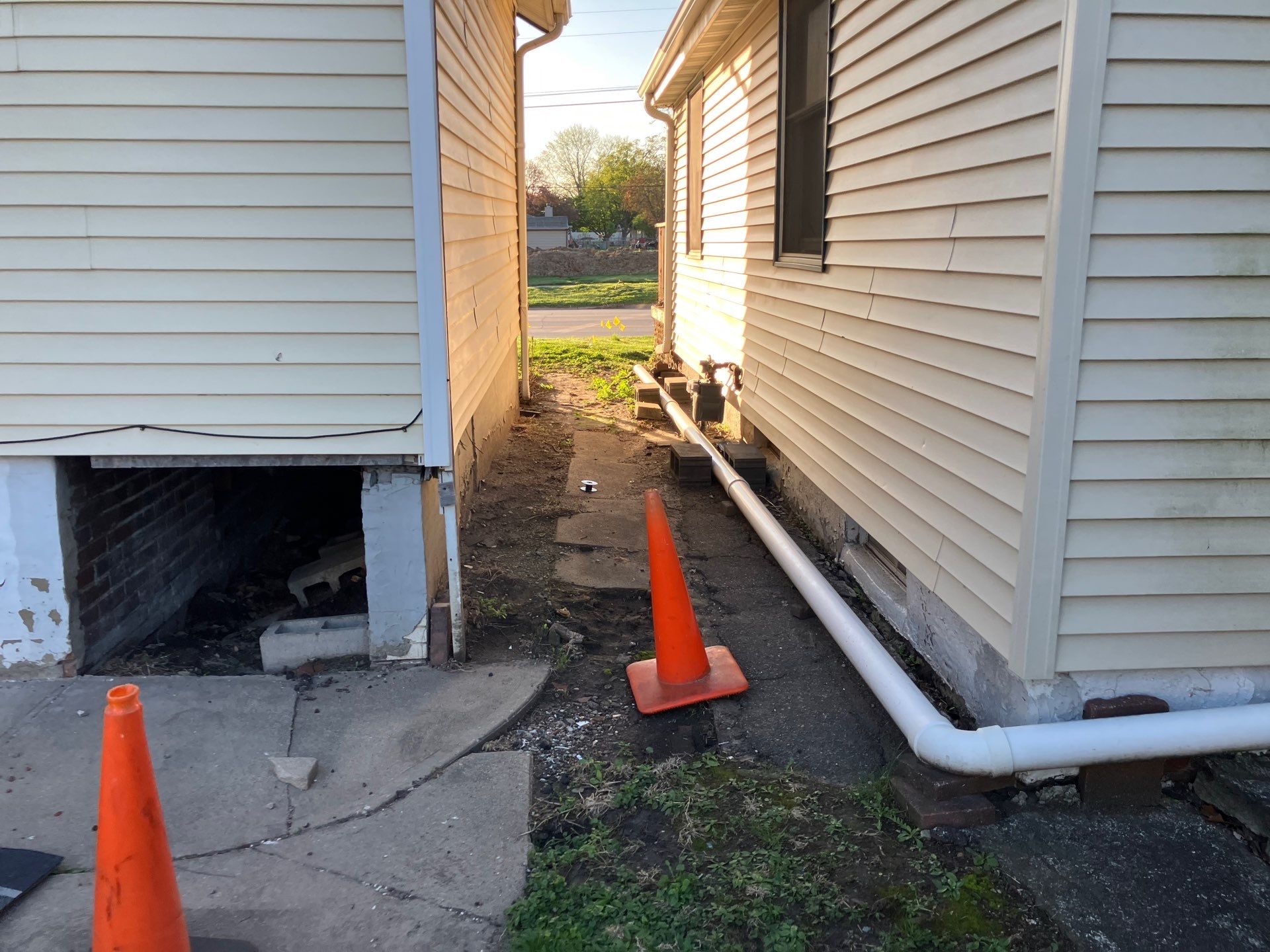 Epp Foundation Repair inspecting exposed crawl space and drainage issues between houses in Des Moines, Iowa.